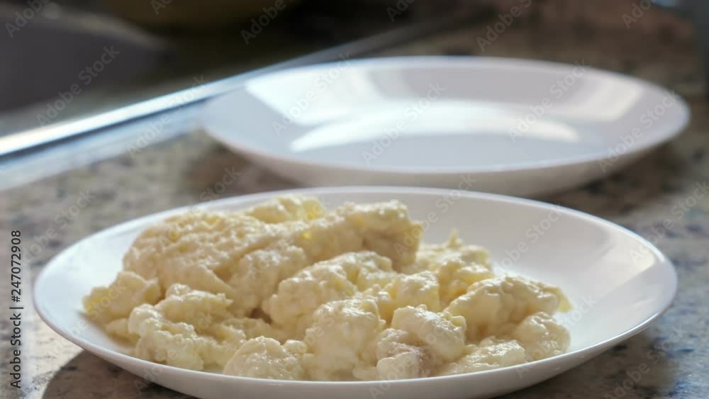 Ready to eat scrambled eggs on white plate at the kitchen, closeup Ready to eat scrambled eggs on white plate at the kitchen, closeup