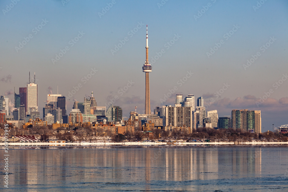 Obraz premium Toronto, CANADA - February 1th, 2019: Panoramic Canadian winter landscape near Toronto, beautiful frozen Ontario lake at sunset. Scenery with winter trees, water and blue sky.