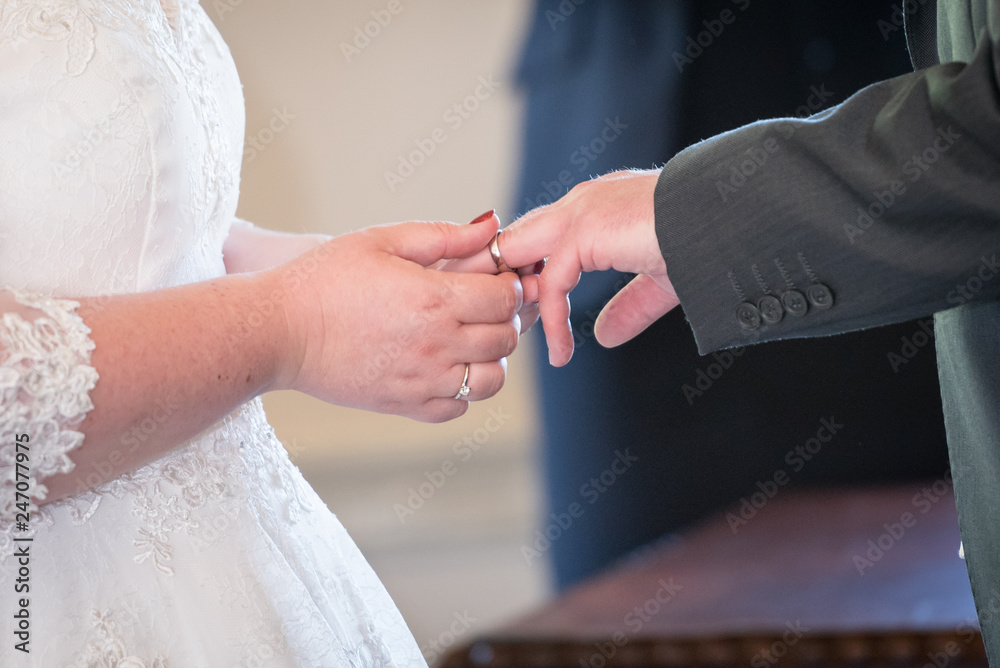 Fototapeta premium Bride placing ring upon grooms finger