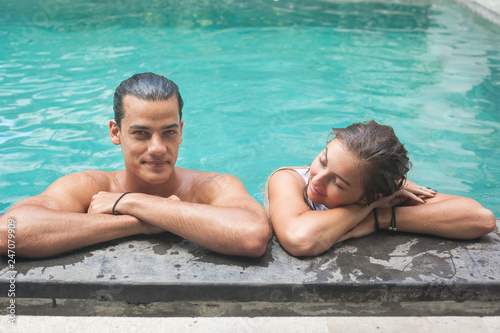 Portrait of a smiling young beautiful couple leaning on a poolside