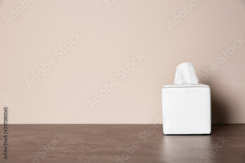 Napkin holder with paper serviettes on table against color background. Space for text