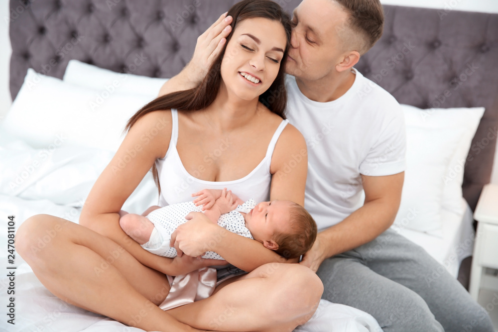 Happy couple with their newborn baby on bed Happy couple with their newborn baby on bed