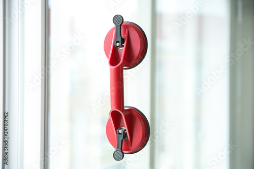 Suction lifter on glass against blurred background. Window installation