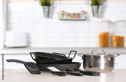 Set of clean cookware and utensils on table in kitchen. Space for text