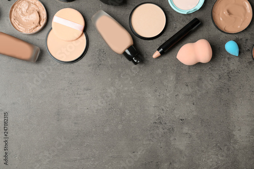 Flat lay composition with skin foundation, powder and beauty accessories on grey background. Space for text