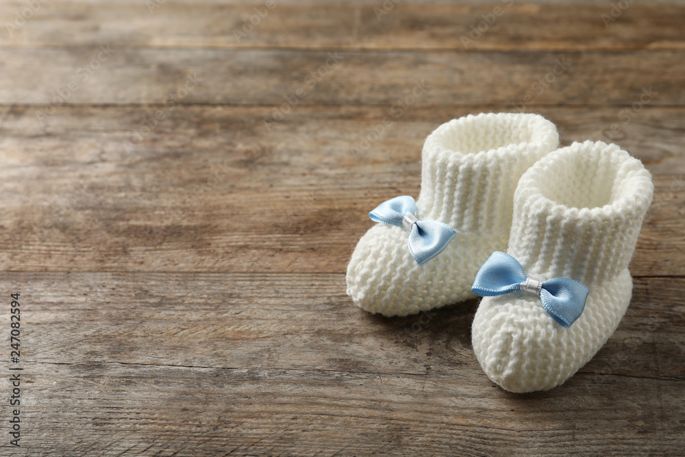 Handmade baby booties on wooden background. Space for text Handmade baby booties on wooden background. Space for text