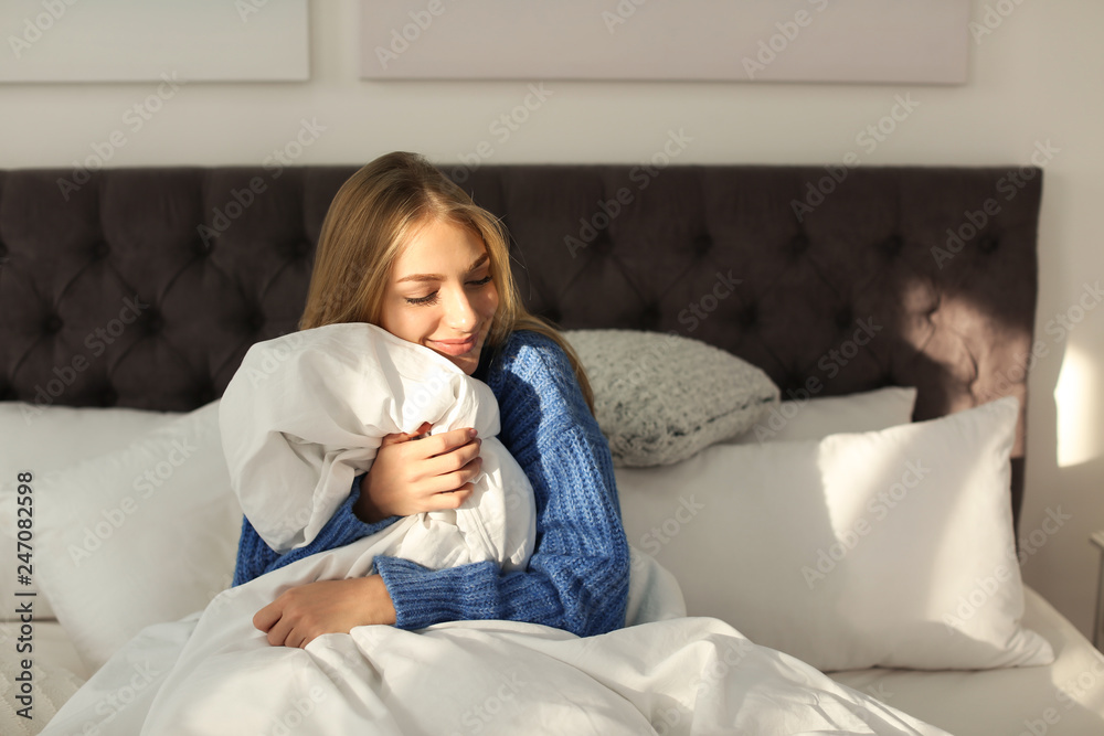 Beautiful young woman hugging soft blanket in bed at home. Winter atmosphere Beautiful young woman hugging soft blanket in bed at home. Winter atmosphere