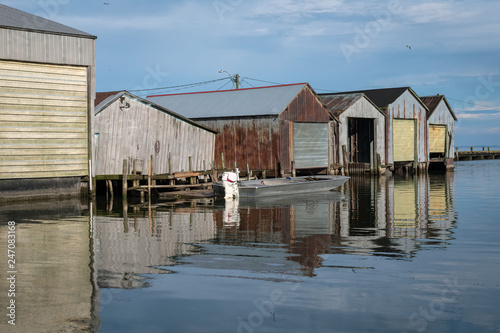 Boat houses reflected in the water.  Image taken on Lake Erie in Port Rowan, Ontario.