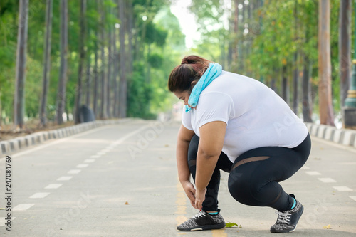 Fat woman tying her shoelaces before jogging