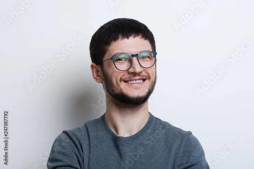 Portrait of smiling young man with glasses over white studio background © Lalandrew