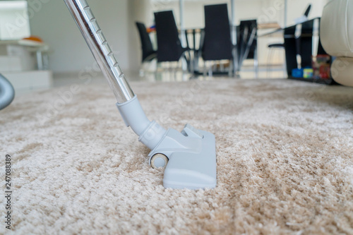 Vacuum cleaner removing dirt on white carpet