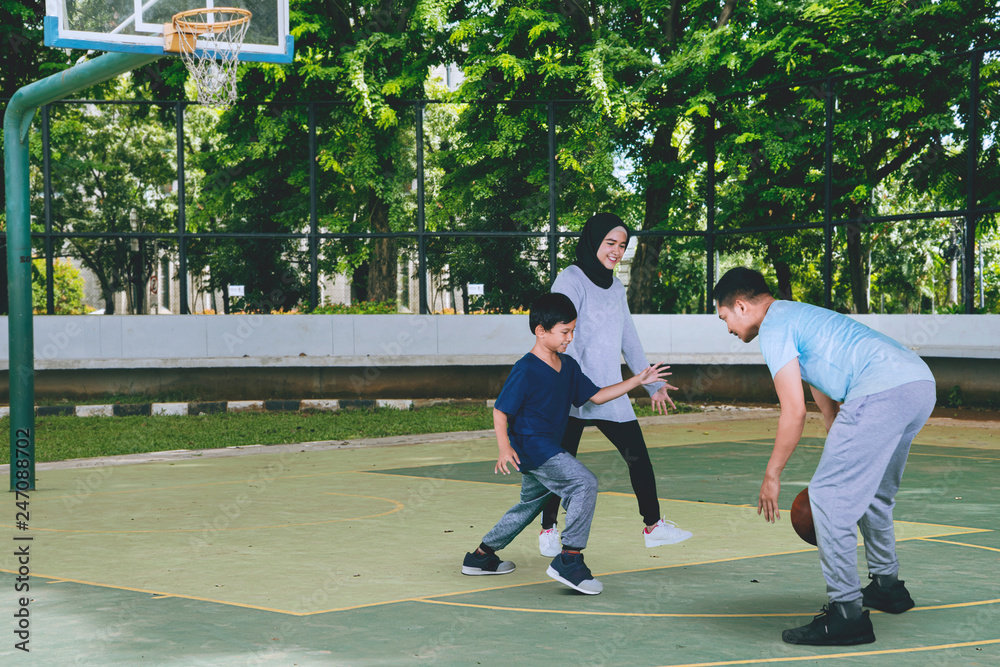 Young man plays basketball with his wife and son