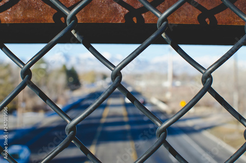 A view through the chain linked fence above the city street in the winter sun. 