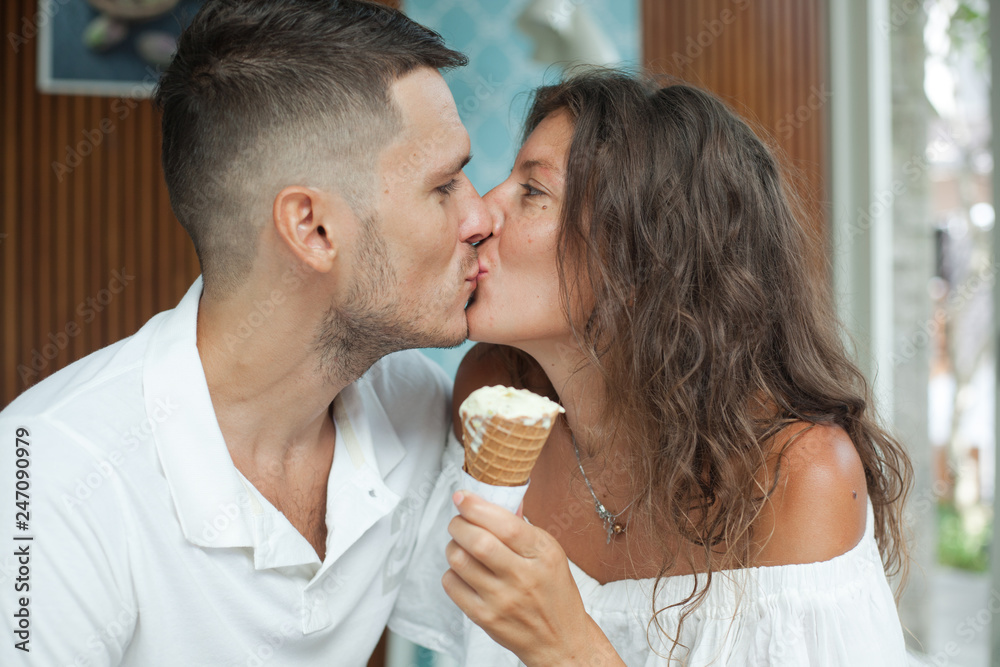 young kissing couple in white is sitting in a cafe. Girl holding ice cream  cone Stock Photo | Adobe Stock