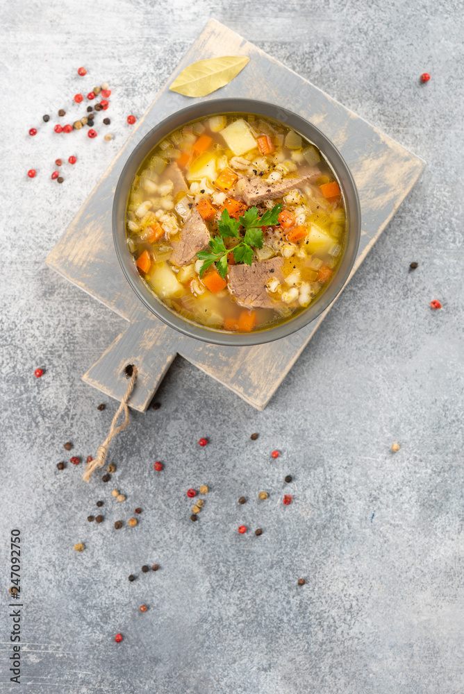 Rassolnik - Traditional Russian soup with pickled cucmbers, pearl barley, meat, pickles, carrots and potatoes on light background. Top view