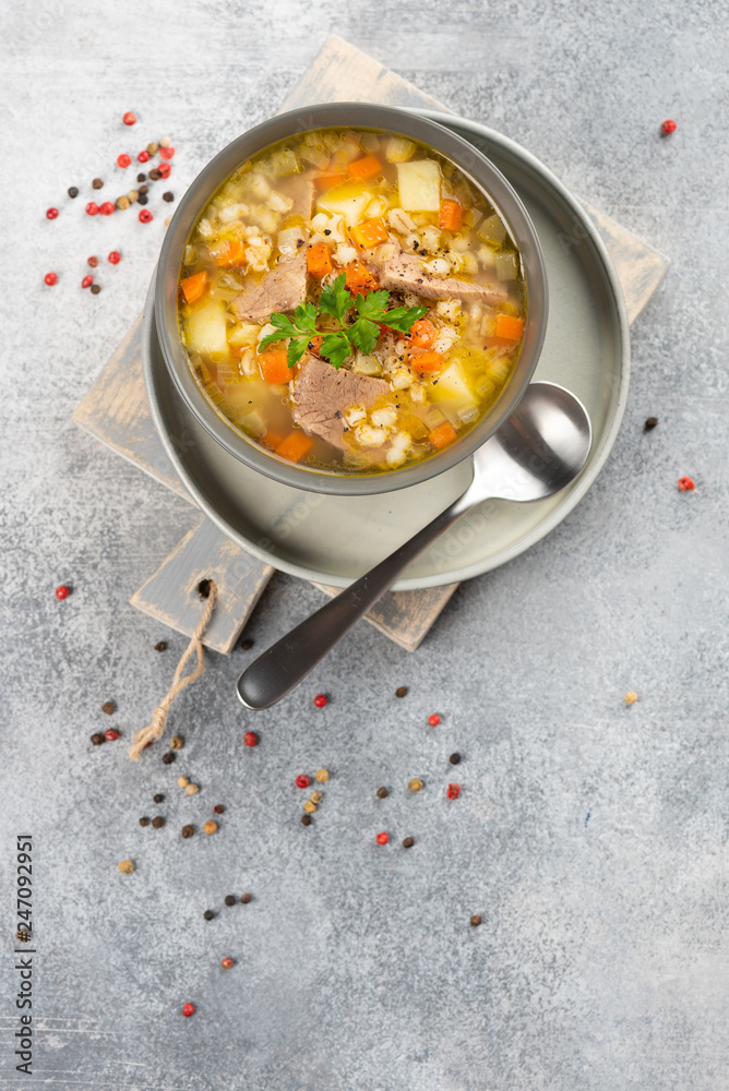 Rassolnik - Traditional Russian soup with pickled cucmbers, pearl barley, meat, pickles, carrots and potatoes on light background. Top view