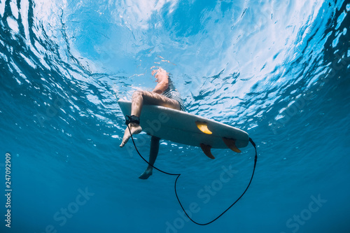 Photography Surfer girl with surfboard relaxing at line up in ocean, underwater