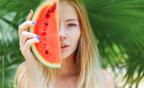 Beautiful young sensual sexy blonde with a slice of red watermelon in palm leaves, beauty and fashion, ecology and nature.
