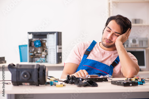 Young male contractor repairing computer  
