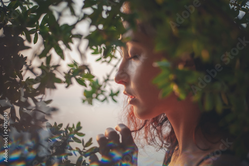 Portrait of a beautiful young woman with dark hair in a frame of branches and green leaves, summer and spring sensual portrait, natural beauty photo