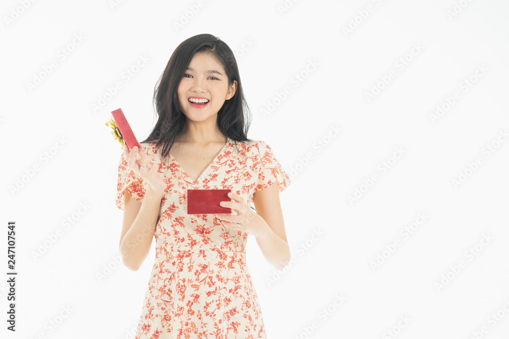 Young woman holding gift box with red bow being excited and surprised holiday present isolated white background Young woman holding gift box with red bow being excited and surprised holiday present isolated white background
