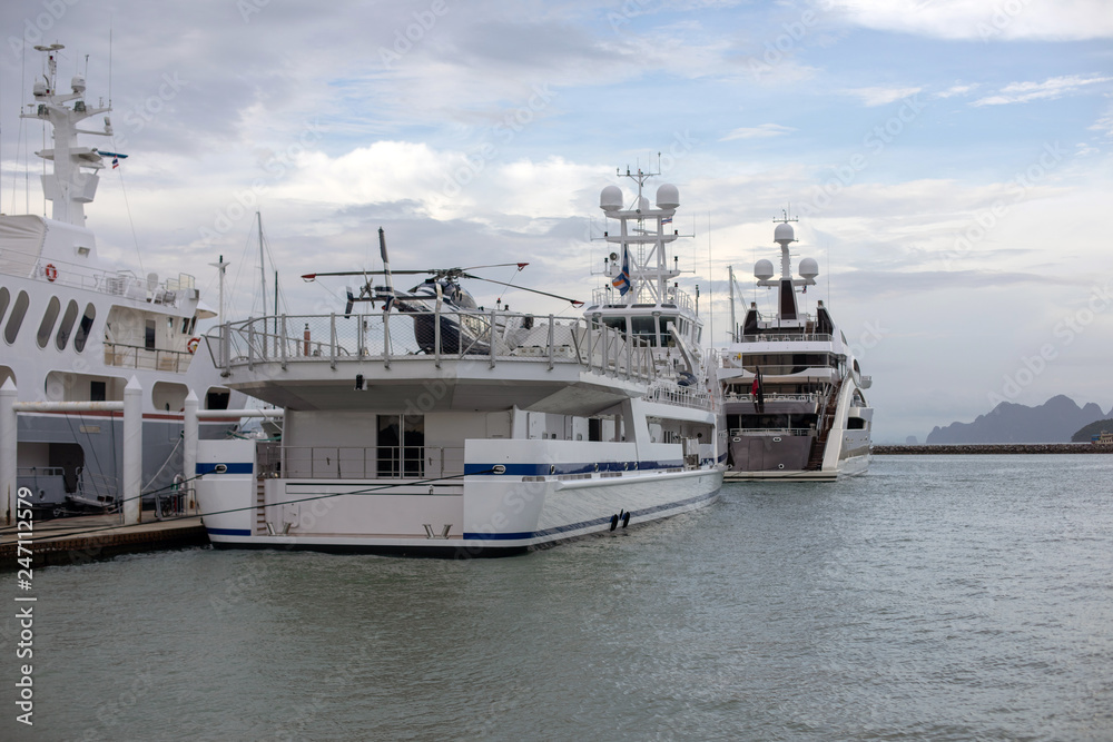 The exotic big white superyachts with helicopter on the roof in port. Thailand. Photo with noise