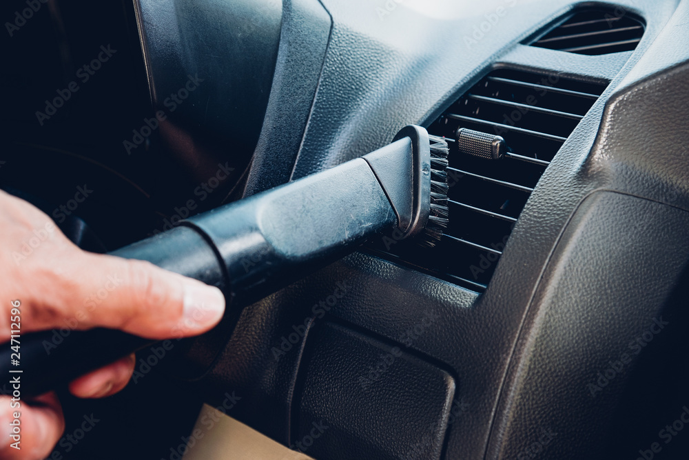 Worker man cleaning dust interior vacuum inside car