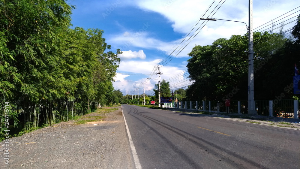 The day in which the sky is bright, with beautiful clouds and asphalt roads in villages with power lines along the road.