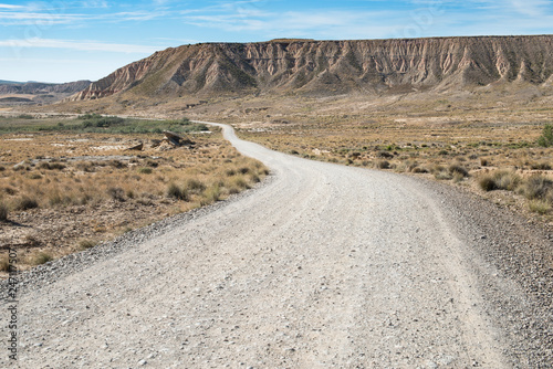 Fototapeta Naklejka Na Ścianę i Meble -  Dirt wild west road to the horizon. American movie vision. Road in desert and rocks mountain on the background.