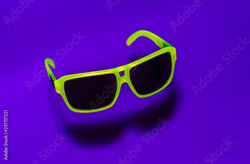 Green floating in the air sunglasses on purple background.