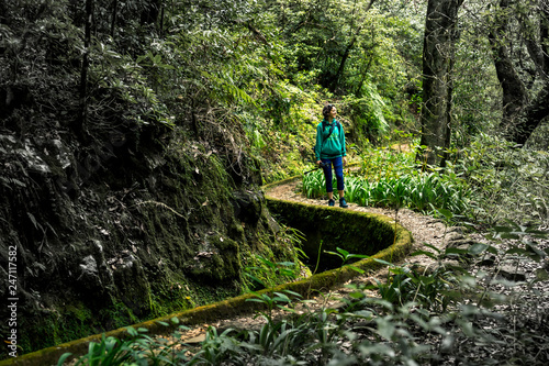 Portrait of young girl in green sweatshirt walking by levana on Madeira island, up in mountains. Hiking by the trail among green, tropical and old forests. Portugal.