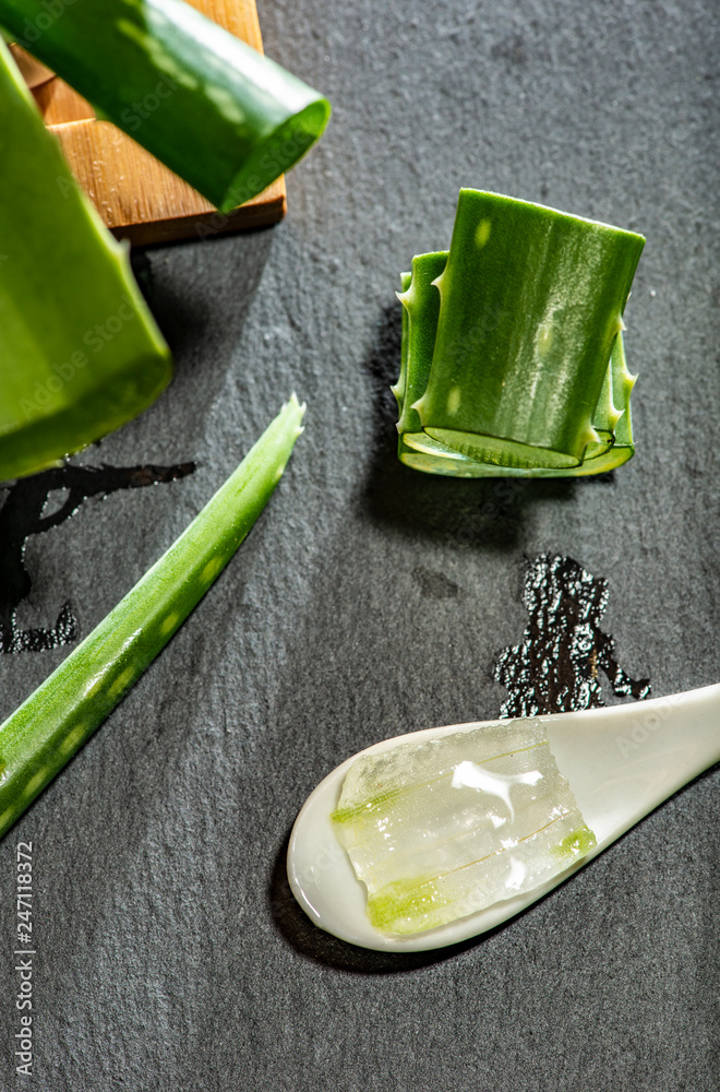 Aloe vera slices on dark background and spoon with aloe gel. Health and beauty concept. Aloe vera slices on dark background and spoon with aloe gel. Health and beauty concept.