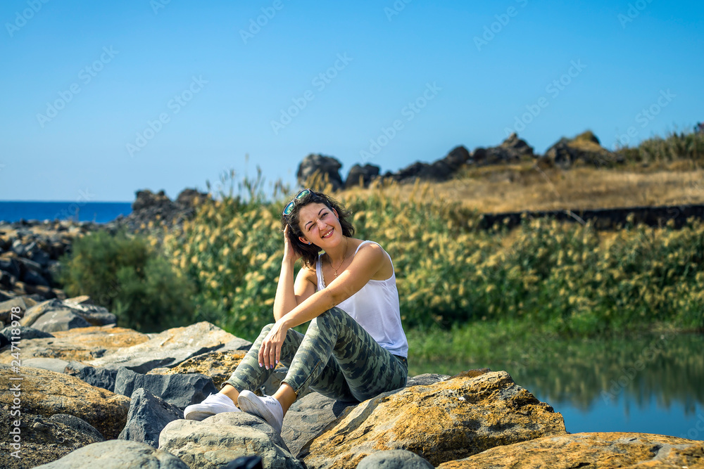 Young and attractive girl in white shirt and sneakers on Madeira's island in some small village with bananas fields on background. Sunny day. Portugal.