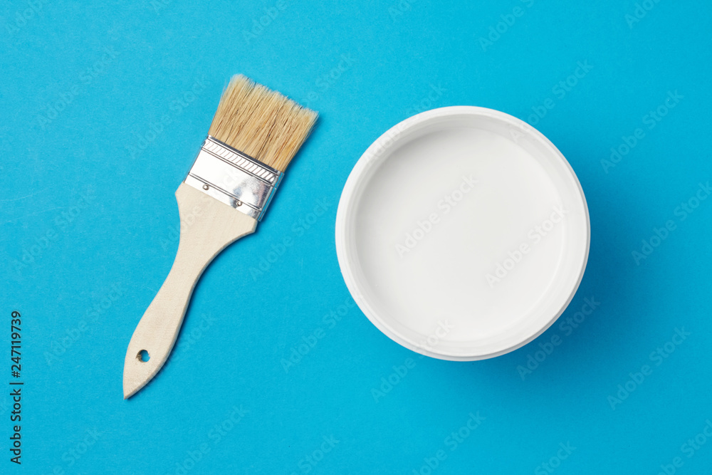 Brush and paint can with white color on a blue background, closeup Brush and paint can with white color on a blue background, closeup