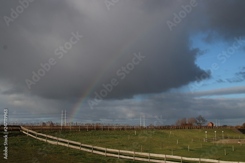 Rainbow with dark rain clouds over river the Rotte in Moerkapelle in the Netherlands.