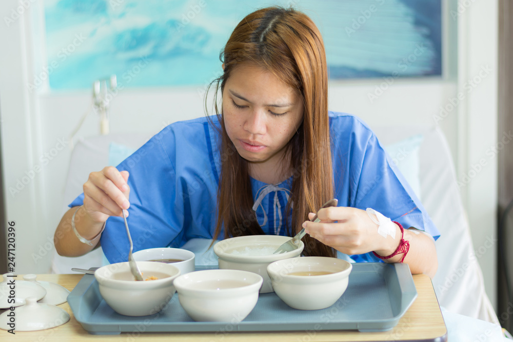 Women patient in blue clothes eat breakfast and take medicine in bed with saline solution on hand lying in hospital room at luxury VIP room, Healthcare Women patient in blue clothes eat breakfast and take medicine in bed with saline solution on hand lying in hospital room at luxury VIP room, Healthcare