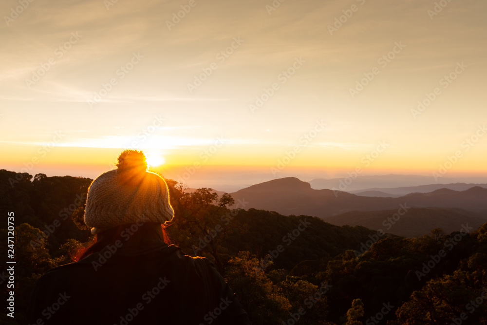 Fototapeta premium The girl wears a winter coat and beautiful winter sunrise landscape viewpoint at km.41 of Doi Inthanon Chiang Mai Thailand.