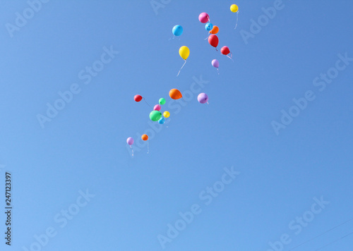 Many released flying balloons in blue sky