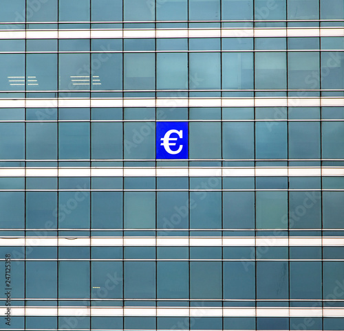 Wallpaper Mural The symbol of the euro currency on the building's window. The glass facade of skyscraper with many identical windows and one window with money sign. Torontodigital.ca
