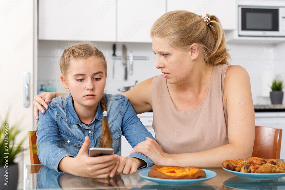 Woman looking into smartphone of her  daughter