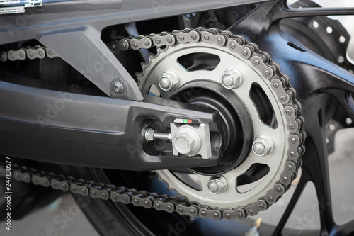 Closeup detail of sport racing motorcycle wheel and swingarm with rear drive o-ring chain and sprocket power transmission from the engine to wheel.