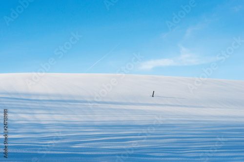 Winter landscape. Hill covered with snow and a blue sky over it