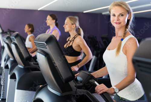 Slender athletic girls running on treadmill in fitness club