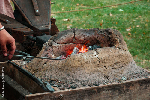 Burning coals in medieval furnace with metal tools and bellows in blacksmith forge