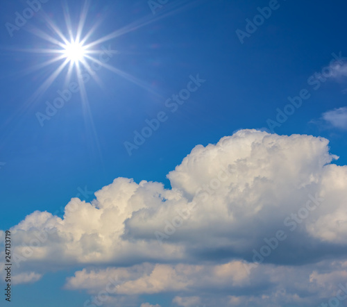 nature background, sparkle sun on a blue sky above a cumulus clouds