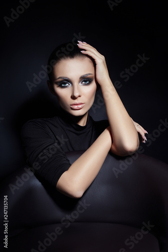 Classic Smokey makeup on woman face, beautiful big eyes. Fashion Perfect makeup, expressive eyes on girl face, smooth black eyebrows, licked brunette hair. Portrait of a woman on a dark background