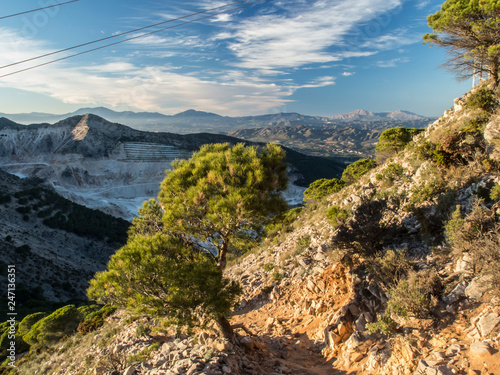 limestone mine in the mountains, with trees in front and sunset light