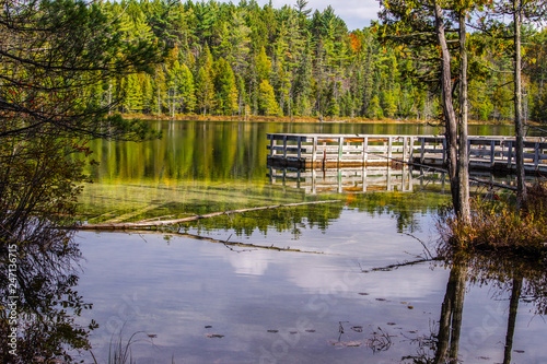 Wilderness Fishing Dock On Lake. Wilderness lake surrounded by a lush northern forest with a fishing dock in Hartwick Pines State Park in Michigan. 