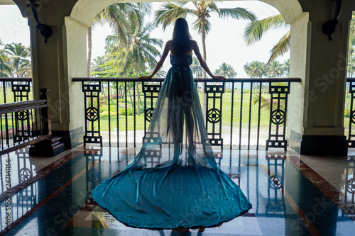 Beautiful bride woman in a gray blue dress with long train is climbs up the stairs in a classic interior. luxury and wealth luxury hotel in tropical paradise botanical garden glass ceiling roof photo