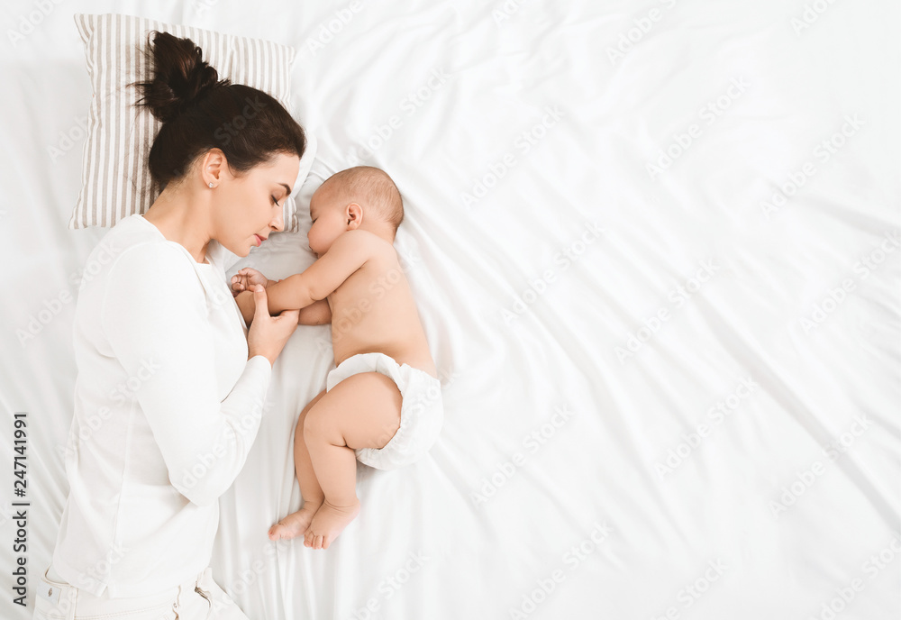 Young mom and her cute baby sleeping in bed - obrazy, fototapety, plakaty 